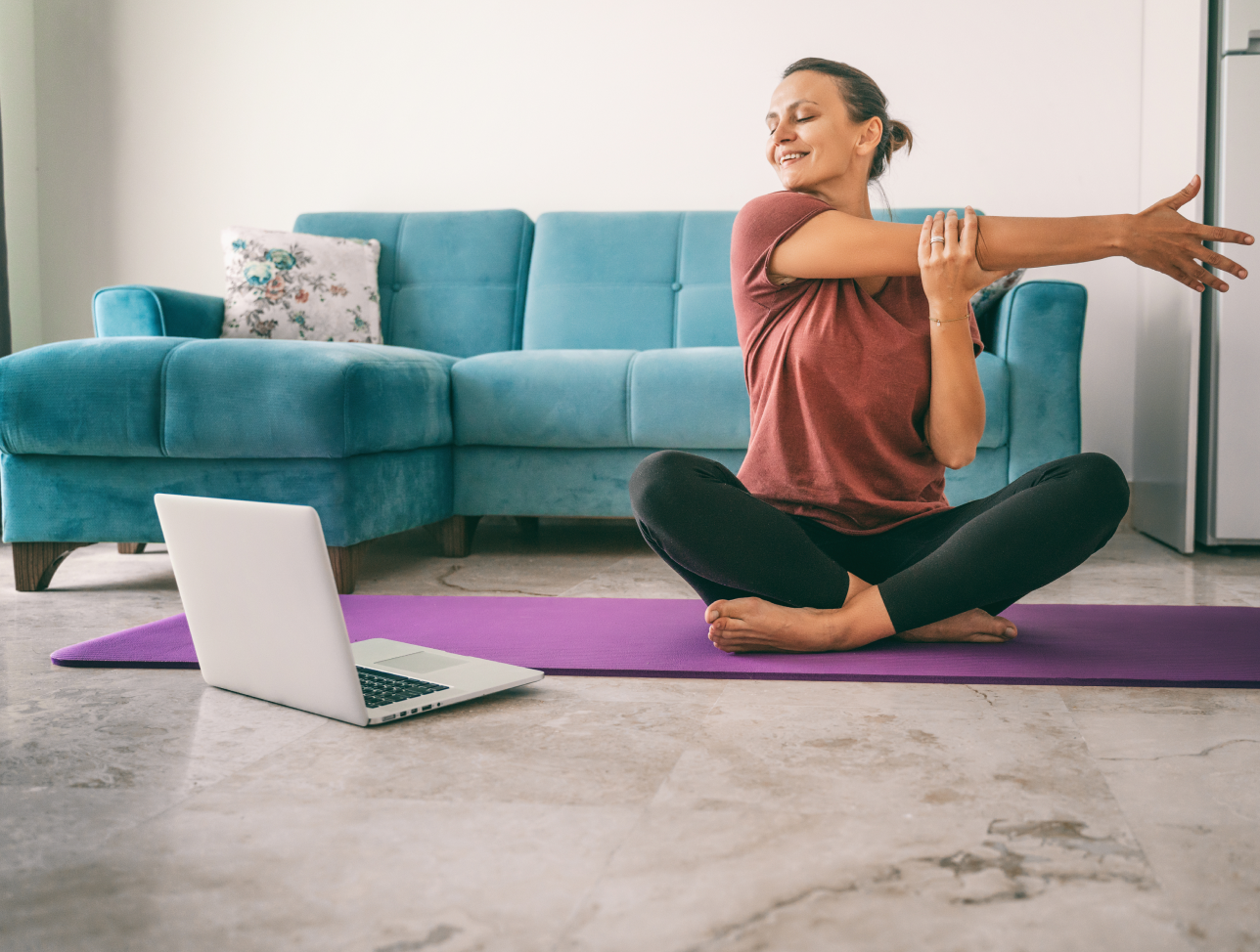 Woman using the internet to stream a yoga class on her laptop.